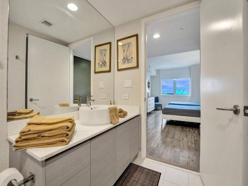 Un baño blanco con lavabo y espejo. en Luxury Waterfront Suite with Great Views, en Hallandale Beach
