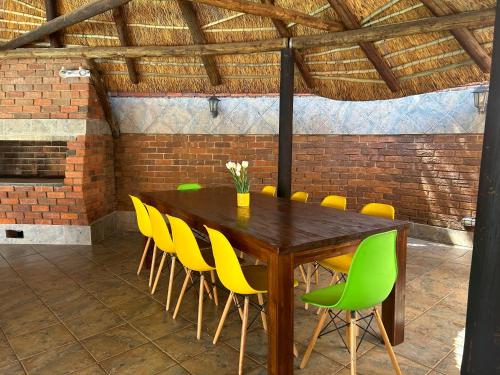 a dining room with a wooden table and yellow chairs at SiBella guest house in Bloemfontein