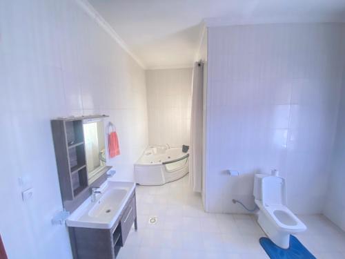 Baño blanco con lavabo y aseo en Luxurious very spacious 6 bedrooms villa with pool located in Gacuriro,close to simba center and a 12mins drive to downtown kigali en Kigali
