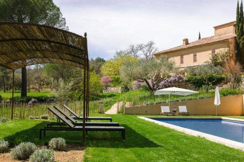 un jardin avec des bancs et une piscine dans l'établissement Domaine Les Vaches, à Cotignac