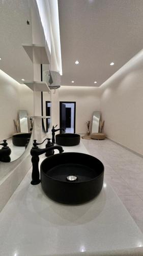 منتجعات رغيد الفندقية في حائل: حمام مع حوض اسود وثلاث مغاسل