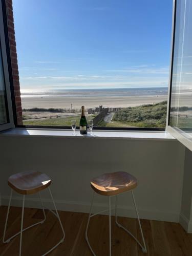 a bar with two stools and a bottle of wine at FACE MER PIEDS DANS L'EAU DUPLEX 4 Chambres 155 M2 8-12 personnes in Berck-sur-Mer