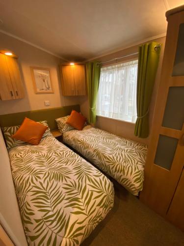 two beds in a small room with a window at Red Squirrel Lodge in Sandown