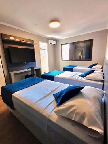 a bedroom with three beds and a flat screen tv at Hotel Bella Paulista in Sao Paulo