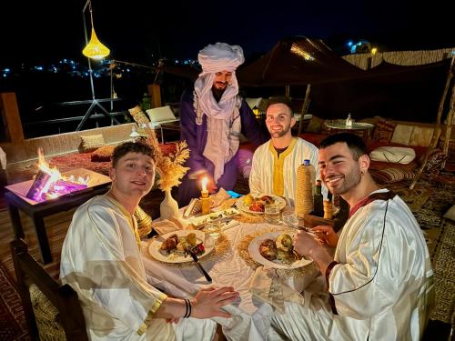 a group of men sitting around a table with food at Riad Sahara Stars Dades in Boumalne