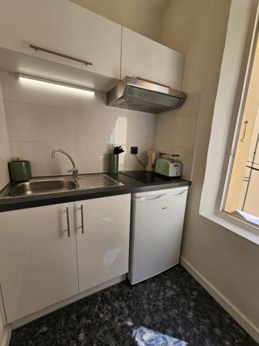 une petite cuisine avec des armoires blanches et un évier dans l'établissement Face port Vauban - En plein cœur du vieil Antibes, à Antibes