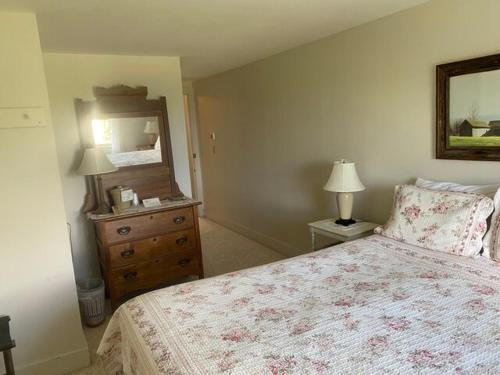 1 dormitorio con cama, tocador y espejo en High Tide Inn on the Ocean, Motel and Cottages, en Camden