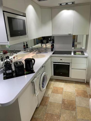 une cuisine blanche avec un évier et un lave-vaisselle dans l'établissement Lovely and calm, à Cannes