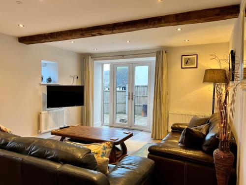 a living room with a leather couch and a table at Cottage - Sleeps 6 - Garden & Parking in Coleford