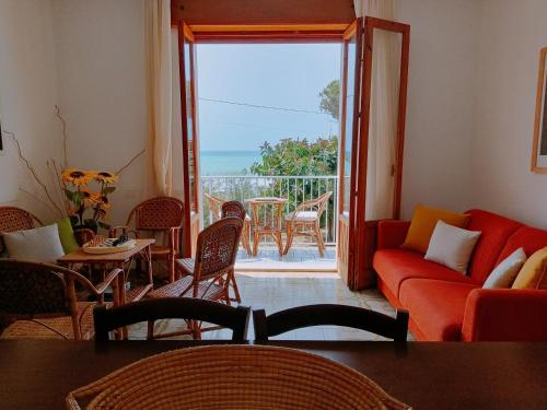 sala de estar con sofá rojo y balcón en Casa Panarea - Villetta indipendente sul mare, en Marina di Modica