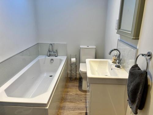 uma casa de banho com uma banheira, um WC e um lavatório. em Stunning 3-Bed Cottage in The Forest of Dean em Coleford