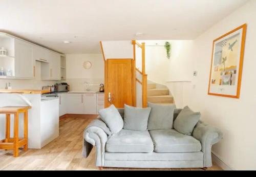 a living room with a couch and a kitchen at Stans Place Self Catering Cottage in Malmesbury