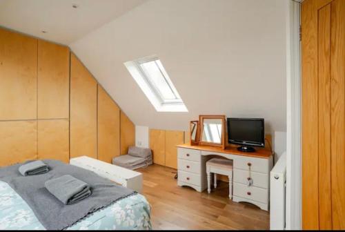 a bedroom with a bed and a desk with a television at Stans Place Self Catering Cottage in Malmesbury