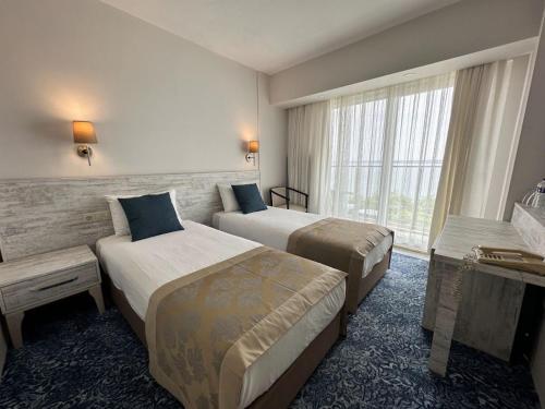 a hotel room with two beds and a window at Kırtay Hotel Erdek in Erdek
