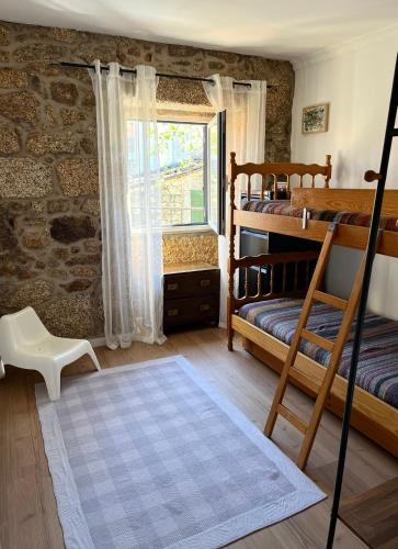 a bedroom with two bunk beds and a window at Casa rústica com terraço e jardim in Águas