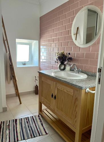 a bathroom with a sink and a pink brick wall at Casa rústica com terraço e jardim in Águas