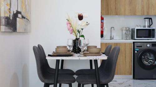 a table with chairs and a vase of flowers on it at 2BR Serene Luxury Retreat - Stylish Getaway in Abu Dhabi