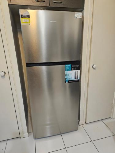a stainless steel refrigerator in a kitchen with white cabinets at Mick's Shared Townhouse in Kallangur