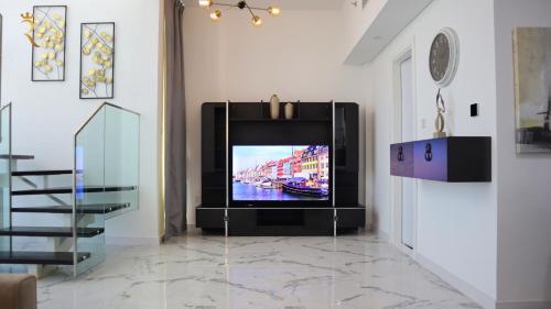 a television in a living room with a staircase at 2BR Serene Luxury Retreat - Stylish Getaway in Abu Dhabi