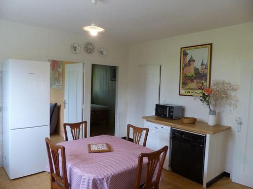 uma cozinha com uma mesa e uma cozinha com um micro-ondas em Gîte Les Hauts de Curemonte em Curemonte