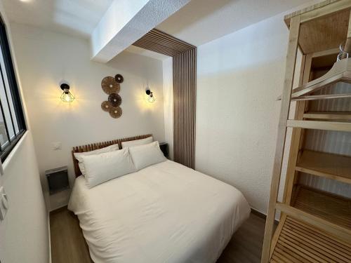 a small bedroom with a white bed and a ladder at Appartement climatisé avec chambre et Parking privatif Locations VLD Camargue in Saintes-Maries-de-la-Mer