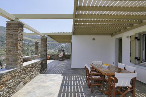 an outdoor patio with a wooden table and chairs at Anchorage Andros Villa in Andros