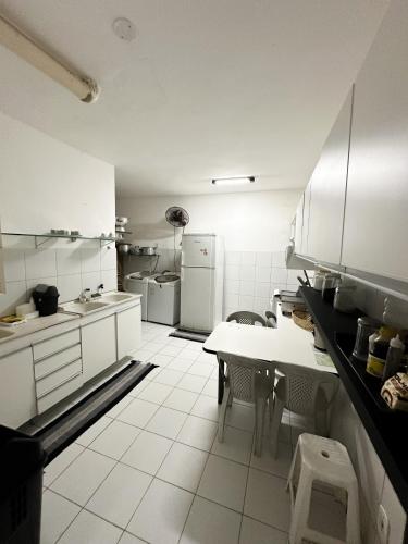a kitchen with white cabinets and a table and chairs at Sua Casa Francês in Marechal Deodoro