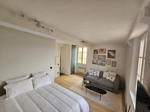 une chambre avec un grand lit blanc et un canapé dans l'établissement Face port Vauban - En plein cœur du vieil Antibes, à Antibes