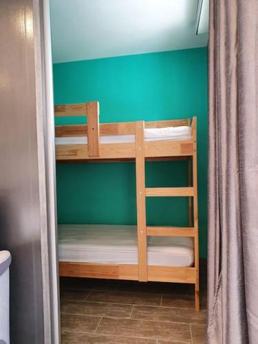 Ce lit superposé se trouve dans un dortoir doté d'un mur vert. dans l'établissement Lacanau Océan, grand confort à 50m de la plage !, à Lacanau-Océan
