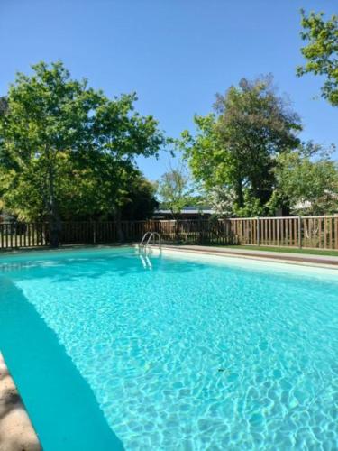 une piscine d'eau bleue en face d'une clôture dans l'établissement Maison Bel Air, à Moliets-et-Maa