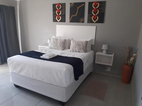 a bedroom with a white bed with a blue blanket at Bonfai Residence in Ermelo