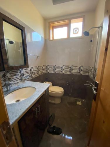 y baño con lavabo, aseo y espejo. en Home of golden oriole, en Hunza