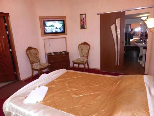 a bedroom with a bed and two chairs and a sink at ApartHotel Dom in Odesa