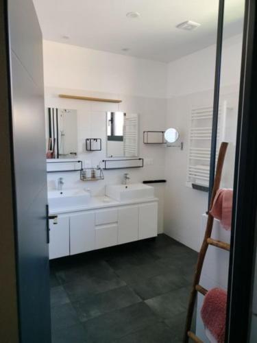 une salle de bain blanche avec deux lavabos et un miroir dans l'établissement Maison Bel Air, à Moliets-et-Maa