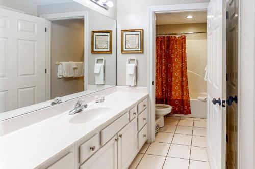 a bathroom with a sink and a toilet and a mirror at Enclave 605 in Orange Beach