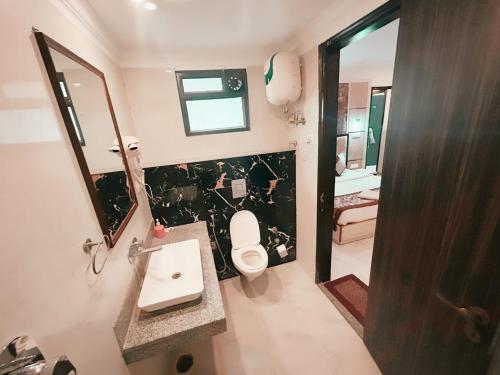 y baño con aseo, lavabo y espejo. en Hotel The Almora Residency Near IGI Airport, en Nueva Delhi