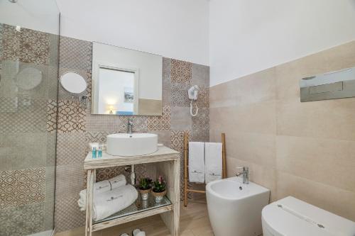 a bathroom with a sink and a toilet and a mirror at Hotel Soffio D'Estate in San Vito lo Capo
