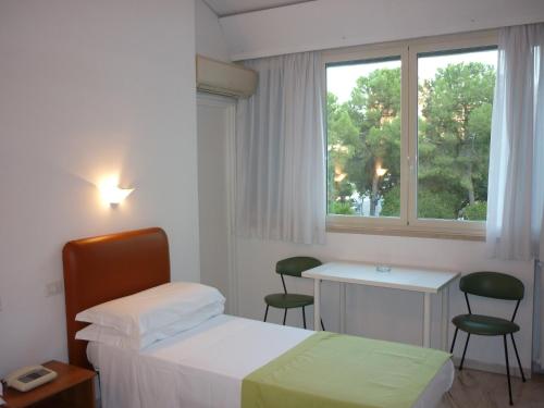 um quarto com uma cama, uma secretária e uma janela em Albergo dei Pini em Andria
