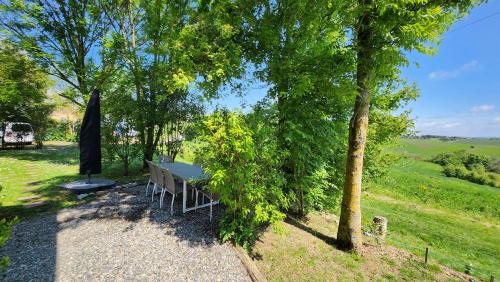 a table and an umbrella in the shade of trees at Gites Souleilla de la Nine in Canens