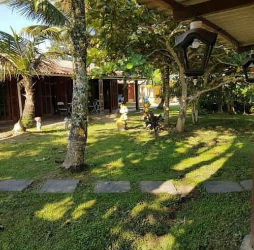 a shady yard with trees and a house at Pousada dos Pescadores - Boraceia in Boracéia