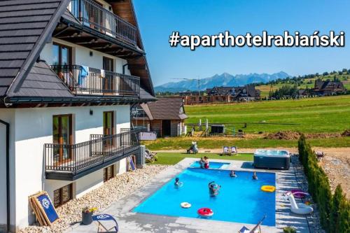 a swimming pool in front of a house with people in it at Apartamenty Borysek De Lux in Białka Tatrzanska
