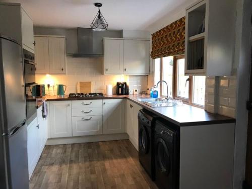 a kitchen with white cabinets and a washer and dryer at River Airebnb in Bradford