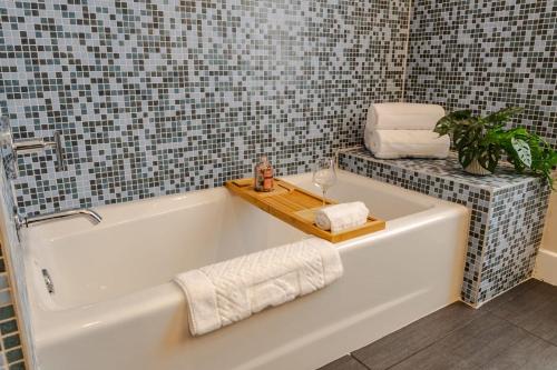a bathroom with a bath tub with a plant and towels at Groovy Condo in the Vibrant NuLu District in Louisville