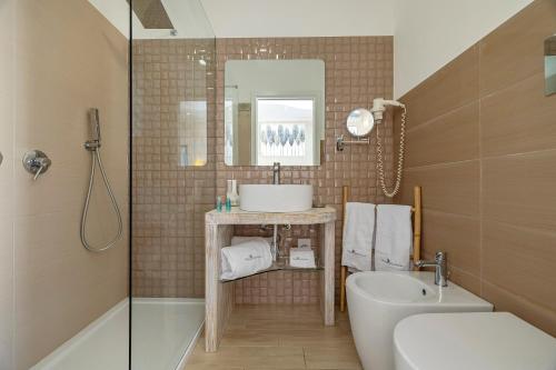 a bathroom with a sink and a toilet and a mirror at Hotel Soffio D'Estate in San Vito lo Capo