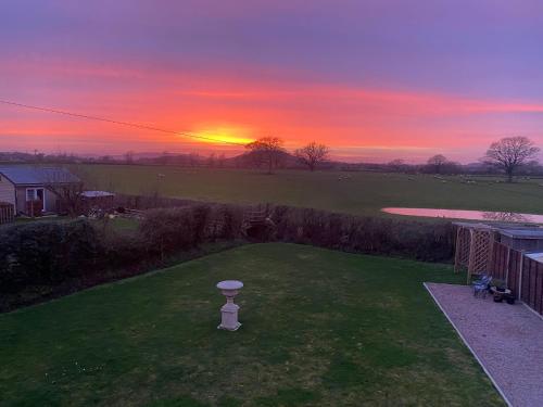 a sunset over a yard with a birdbath in the grass at Hillvine in Hartpury