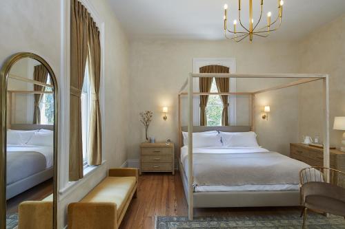 a bedroom with a canopy bed and two windows at Heights House Hotel in Raleigh