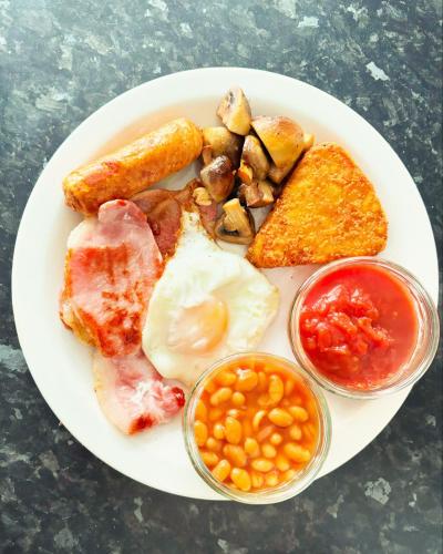 a plate of breakfast food with eggs bacon beans and toast at Ivydene Guest House in Skegness