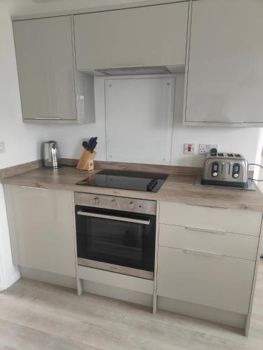 a kitchen with white cabinets and a stove top oven at Beach Break Aberavon Holiday Home by the Sea in Port Talbot