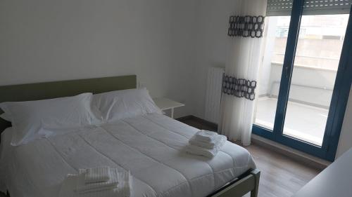 Schlafzimmer mit einem Bett mit weißer Bettwäsche und einem Fenster in der Unterkunft Welcome Appartamenti in Matera