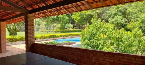 un patio al aire libre con piscina y pared de ladrillo en Recanto Saira, en Caeté